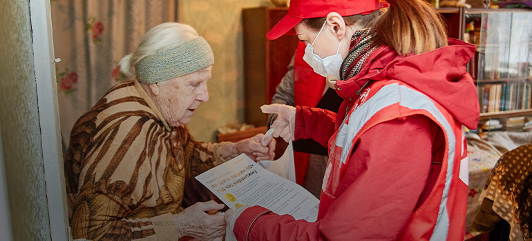 A Red Cross staff member reviews a document with an elderly woman.